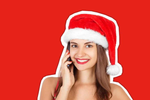 Счастливая красивая девушка в рождественской шляпе разговаривает по мобильному телефону. Журнальный стиль коллажа с тривиальным цветовым фоном. Концепция новогодних и рождественских каникул — стоковое фото