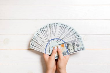 Renkli arka planda para fan tutarak kadın el üst görünümü. 100 dolarlık banknotlar. Kredi ve borç kavramı.