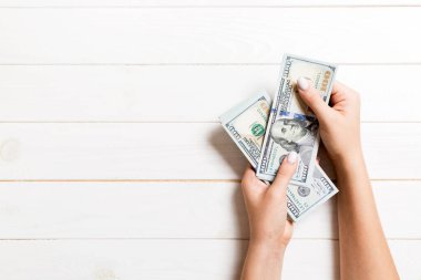 Bir iş kadınının elleri ahşap arka planda 100 dolarlık banknotları sayıyor. Kopya alanı ile başarı ve zenginlik kavramı