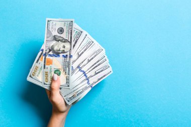 Kadın elinin rengarenk arka planda bir para yelpazesini tutuş görüntüsü. Yüz dolarlık banknotlar. Kopya alanı ile kredi ve borç kavramı