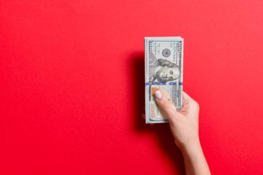 Kadın el renkli arka plan üzerinde para bir demet tutan. 100 dolarlık banknotların en iyi görünümü. Tasarım için boş alan ile Maaş kavramı
