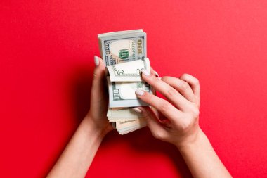 Renkli arka planda bir iş kadınının 100 dolarlık banknotları saymasının en üst görüntüsü. Başarı ve zenginlik kavramı
