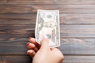 Ahşap arka planda elli dolarlık banknot tutan bir kadın. Maaş ve ücret kavramı