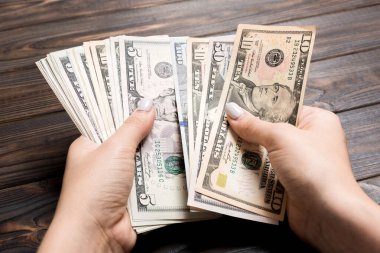 İş kadınının elleri ahşap arka planda farklı dolarları sayıyor. Maaş ve maaş kavramı. Yatırım konseptinin en üst görünümü