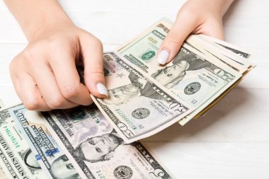 Kadın ellerinin para saymasına bakış açısı. Ahşap arka planda farklı dolar banknotları. İş konsepti