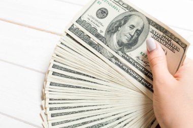 Ahşap arka plan üzerinde para fan tutarak kadın el Perspektif görünümü. 100 dolarlık banknotlar. Kredi ve borç kavramı