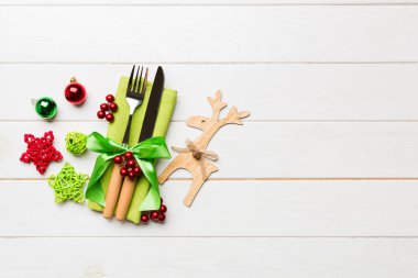 Yeni yıl çatal ve bıçak seti peçeteye. Noel süslerinin ve ahşap arka plandaki ren geyiklerinin en üst görüntüsü. Tasarımınız için boş alanı olan tatil aile yemeği konsepti