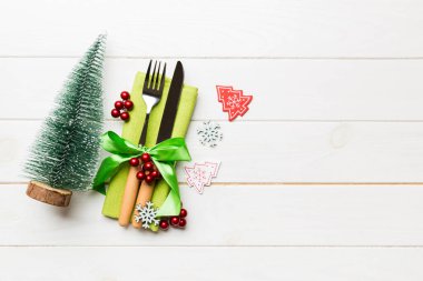 Çatal ve bıçağın üst görüntüsü ahşap arka planda peçeteyle bağlanmış. Noel süsleri ve yılbaşı ağacı. Tasarımınız için boş alanı olan mutlu tatil kavramları