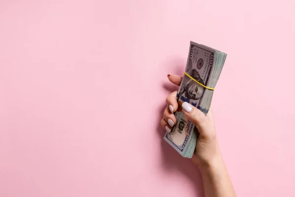 Balík 100 dolarových bankovek v ženských rukou na barevném pozadí. Finanční a obchodní koncepce s prostorem pro kopírování — Stock fotografie
