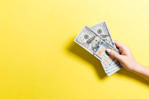 Ženská ruka drží balík peněz na barevném pozadí. Nejvyšší pohled na 100 dolarových bankovek. Koncept mezd s prázdným místem pro návrh — Stock fotografie