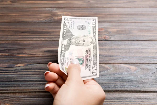 Ženská ruka drží padesátidolarovou bankovku na dřevěném pozadí. Koncepce mezd a platů — Stock fotografie