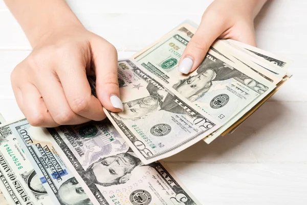 Vista prospettiva delle mani femminili che contano i soldi. Banconote diverse in dollari su fondo di legno. Concetto aziendale — Foto Stock