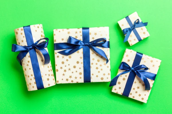 Wrapped Christmas or other holiday handmade present in paper with blue ribbon on green background. Present box, decoration of gift on colored table, top view — Stock Photo, Image