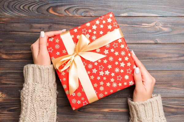 Bovenaanzicht van vrouwelijke handen met kerst of andere vakantie handgemaakte geschenkdoos pakket in de handpalmen, platte lay tafel achtergrond met kopieerruimte — Stockfoto