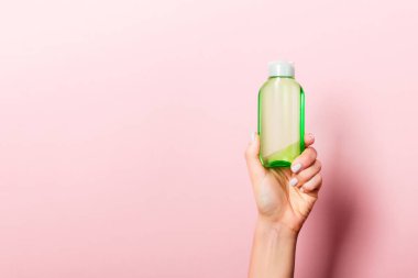 Kadın el tutarak krem şişe losyon izole. Kız pembe arka plan üzerinde tüp kozmetik ürünleri vermek