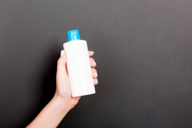 Kadın el tutarak krem şişe losyon izole. Kız siyah arka plan üzerinde tüp kozmetik ürünleri vermek