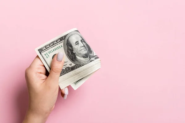 Um pacote de notas de cem dólares na mão feminina sobre fundo colorido. Conceito salarial com espaço de cópia — Fotografia de Stock