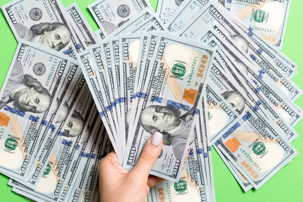 Pohled na ženské ruce ležící na hromadě 100 dolarových bankovek. Koncepce úspěchu a bohatství na barevném pozadí — Stock fotografie