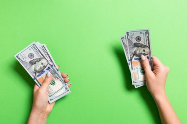 Kadın eli biraz para veriyor, 100 dolarlık banknotları yakın plan sayıyor. Renkli arkaplan üzerine iş kavramı