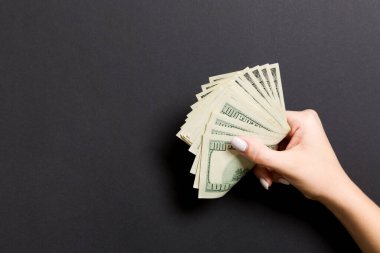 Renkli arka planda kadın elinde yüz dolarlık banknotlar bir paket. Kopya alanı ile maaş kavramı