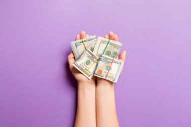 Renkli arka planda kadın avuçlarında dolar banknotlarının üst görüntüsü. Yoksulluk ve borç kavramı