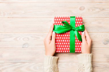 Sarı rustik ahşap masa zemininde renkli kurdeleli hediye paketi, üst görünüm kopyalama alanı