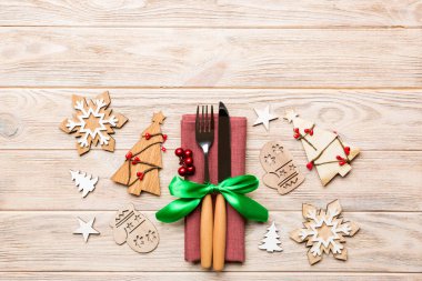 Çatal ve bıçağın üst görüntüsü ahşap arka planda peçeteyle bağlanmış. Noel süsleri ve yılbaşı ağacı. Tasarımınız için boş alanı olan mutlu tatil kavramları