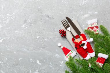 Çimento arka planındaki Noel süslerinin en üst görüntüsü. Peçetedeki çatal ve bıçak kurdeleyle bağlanmış ve senin tasarımın için boş bir alan. Yeni yıl şablonu kavramı