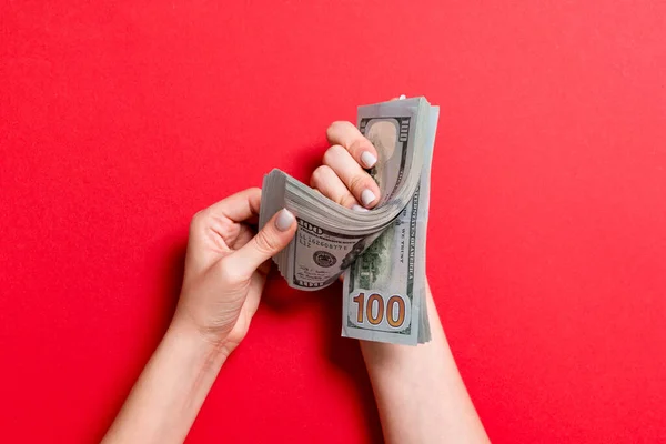 Vista superior de las manos de una mujer de negocios contando billetes de cien dólares sobre un fondo colorido. Concepto de éxito y riqueza — Foto de Stock