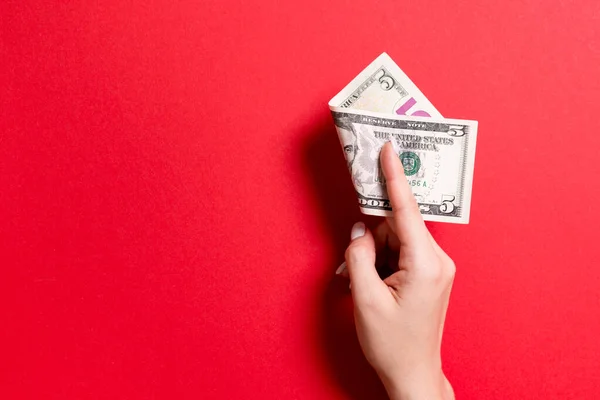 Vista superior de la mano femenina sosteniendo un paquete de dinero sobre un fondo colorido. Cinco dólares. Concepto de negocio con espacio vacío para su diseño. Concepto de caridad y consejos — Foto de Stock