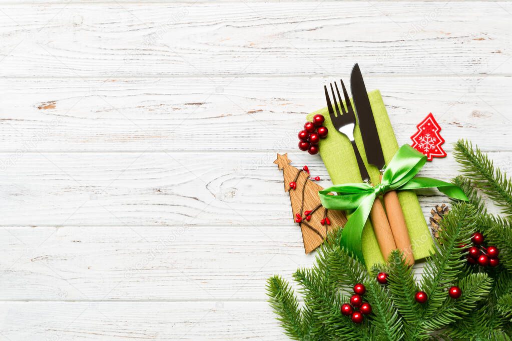 Top view of fork and knife on napkin with christmas decorations and new year tree on wooden background. Holiday and festive concept with copy space