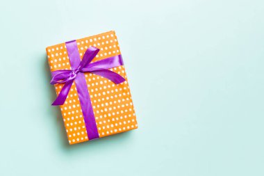 Noel 'i ya da diğer tatil hediyelerini mavi arka planda mor kurdeleli kağıda sardım. Şimdiki kutu, renkli tabloda hediye süslemesi, kopya alanı ile üst görünüm