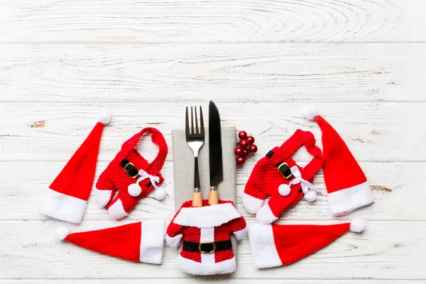 Festive set of fork and knife on wooden background. Top view of new year decorations and santa clothes and hat. Christmas concept with copy space — Stock Photo, Image