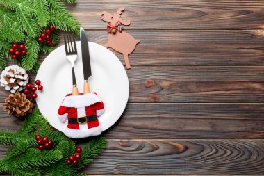 Ahşap arka planda Noel yemeğinin en üst görüntüsü. Tabak, kap kacak, köknar ağacı ve kopyalanmış tatil süslemeleri. Yeni yıl konsepti