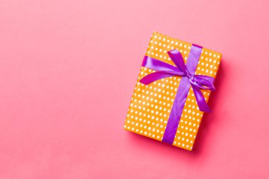 Yaşayan mercan arka planında mor kurdeleli el yapımı Noel hediyeleri. Şimdiki kutu, renkli tabloda hediye süslemesi, kopya alanı ile üst görünüm