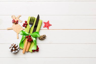 Yeni yıl çatal ve bıçak seti peçeteye. Noel süslerinin ve ahşap arka plandaki ren geyiklerinin en üst görüntüsü. Tasarımınız için boş alanı olan tatil aile yemeği konsepti