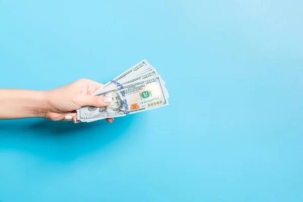 Imagen de la mano femenina sosteniendo un paquete de dólares sobre fondo azul. Concepto de pago — Foto de Stock