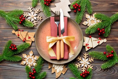Çatal bıçak takımının ve tabağın en üst görüntüsü şenlikli ahşap arka planda. Yeni yıl aile yemeği konsepti. Firavun ağacı ve Noel süslemeleri