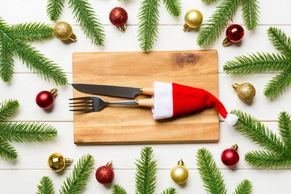 Blick von oben auf Gabel, Messer und Teller umgeben von Tannenbaum und Weihnachtsschmuck auf Holzgrund. Silvester und Feiertagsessen-Konzept — Stockfoto