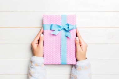 Kadın ellerinin Noel 'i ya da diğer tatil el yapımı hediye paketlerini avuçlarında tutuşu, fotokopi alanı olan düz masa arkaplanı.