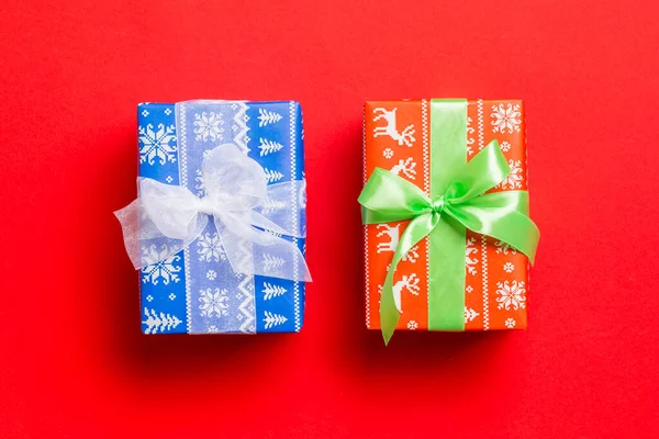 赤の背景に白と緑のリボンで紙にクリスマスや他の休日の手作りプレゼントを包んだ。プレゼントボックス、カラーテーブルのギフトの装飾、トップビュー — ストック写真