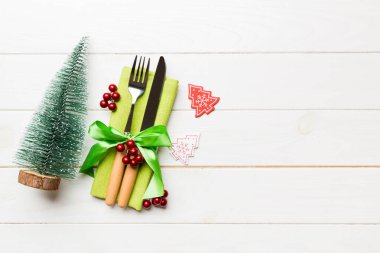 Çatal ve bıçağın üst görüntüsü ahşap arka planda peçeteyle bağlanmış. Noel süsleri ve yılbaşı ağacı. Tasarımınız için boş alanı olan mutlu tatil kavramları