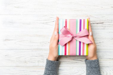 Beyaz, ahşap arka planda kopyalanmış fiyonk ile süslenmiş ve paketlenmiş hediye tutan kadınların düz uzantıları. Noel ve tatil konsepti