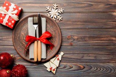 Noel süslenmiş ahşap arka planda servis edilen tabağın, çatalın ve bıçağın üst görüntüsü. Kopya alanı ile Yeni Yıl Arifesi kavramı