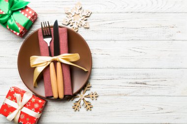 Noel süslenmiş ahşap arka planda servis edilen tabağın, çatalın ve bıçağın üst görüntüsü. Kopya alanı ile Yeni Yıl Arifesi kavramı