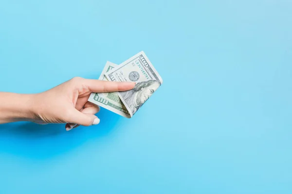 Billetes de dólar en mano femenina sobre fondo azul. Concepto empresarial — Foto de Stock
