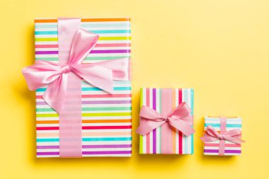 Noel 'de pembe fiyonklu hediye kutusu ya da sarı arka planda yeni yıl günü, üst manzara