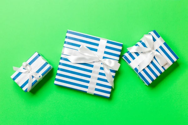 用绿色背景的白色缎带包装圣诞礼物或其他手工制作的节日礼物。礼物盒，彩色桌上的礼物装饰，顶视图 — 图库照片