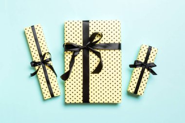Kağıda sarılmış Noel ya da diğer tatil hediyeleri mavi arka planda siyah kurdeleyle. Hediye kutusu, hediye dekorasyonu renkli masa, üst görünüm