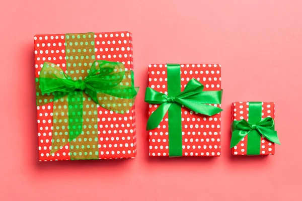 Zabalené vánoční nebo jiné sváteční ručně vyráběné dárek v papíru se zelenou stuhou na živém korálovém pozadí. Dárek box, dekorace dárku na barevném stole, pohled shora — Stock fotografie